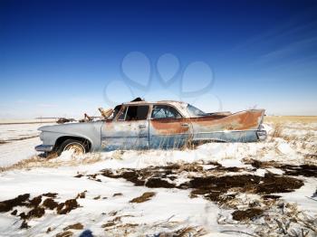 Royalty Free Photo of a Classic Rusted Car in a Snowy Junkyard