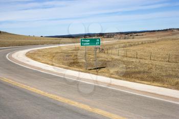 Royalty Free Photo of a Winding Road in South Dakota With Mileage Distance Road Sign