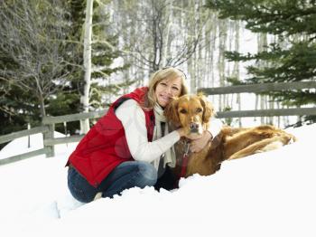 Royalty Free Photo of a Woman Hugging a Dog and Smiling in a Snow Covered Colorado Landscape
