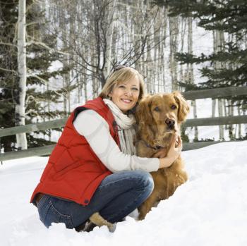 Royalty Free Photo of a Woman Hugging a Dog and Smiling in a Snow Covered Colorado Landscape