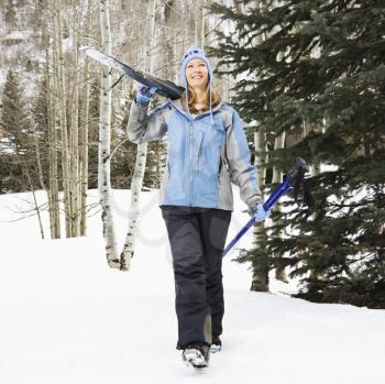 Royalty Free Photo of a Female Skier Walking and Carrying Skis on Her Shoulder