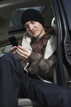 Caucasian male teenager text messaging with cellphone.