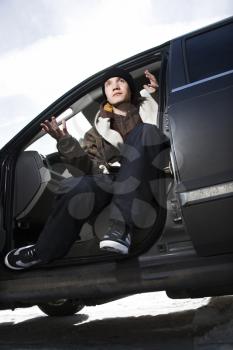 Royalty Free Photo of a Confident Male Teenager Sitting in a Car Making a Hand Gesture