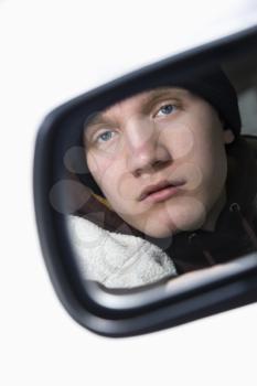 Royalty Free Photo of a Male Teenager Looking at Himself in a Side View mirror of a Car
