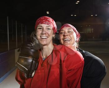 Royalty Free Photo of Women Hockey Players in Uniform Posing With Helmets off on an Ice Rink