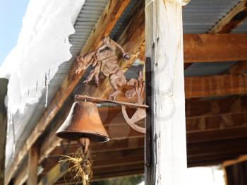 Royalty Free Photo of a Rusted Bell on a Side Post of a Shed