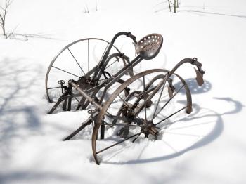 Royalty Free Photo of a Classic Metal Plow Sitting in a Snow Covered Field