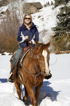 Royalty Free Photo of a Woman Horseback Riding in Snow and Smiling