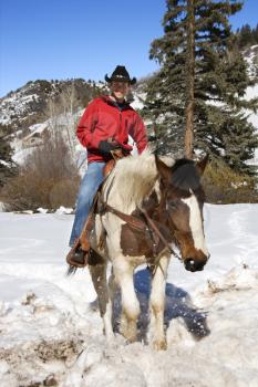Royalty Free Photo of a Man Horseback Riding in the Snowy Mountains