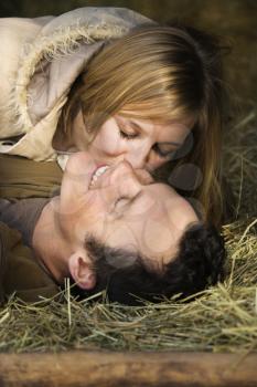 Royalty Free Photo of a Woman Kissing Her Boyfriend While Lying in Hay