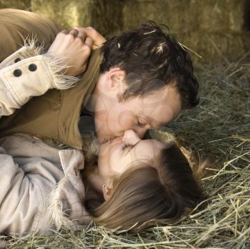 Royalty Free Photo of a Couple Lying Down in Hay Kissing