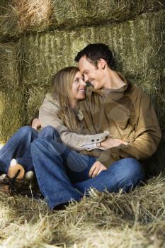 Royalty Free Photo of a Couple Sitting on Hay Hugging and Smiling