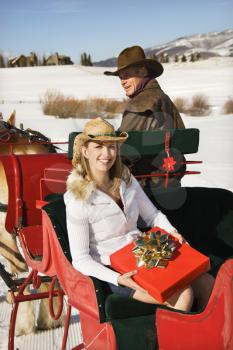 Royalty Free Photo of a Woman Holding a Present While a Man Drives a Horse-Drawn Sleigh