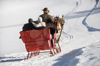 Royalty Free Photo of a Man Driving a Horse Drawn Sleigh With a Young Couple