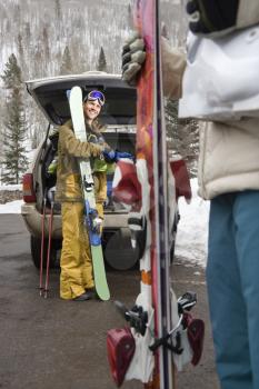 Royalty Free Photo of a Couple Standing by a Vehicle With Ski Equipment