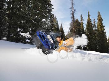 Royalty Free Photo of a Young Man Digging Out a Snowmobile Submerged in the Snow