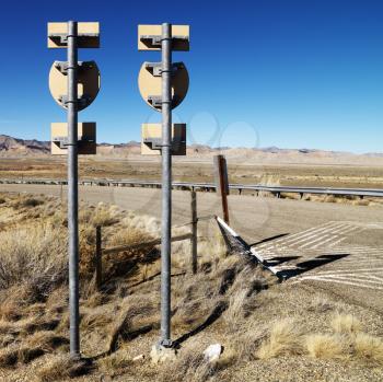 Royalty Free Photo of Two Road Signs on a Post With a Guardrail and Mountains in the Background