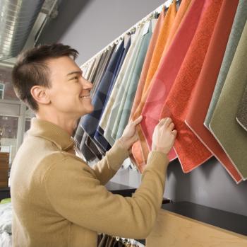 Royalty Free Photo of a Man Looking at Fabric Swatches in a Retail Store