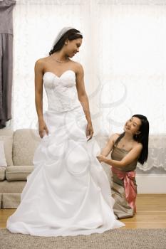 Royalty Free Photo of a Bridesmaid Fixing a Bride's Dress