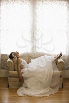 Royalty Free Photo of a Bride Laying on a Love Seat