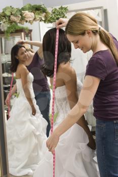 Royalty Free Photo of a Seamstress Measuring a Bride in a Bridal Shop