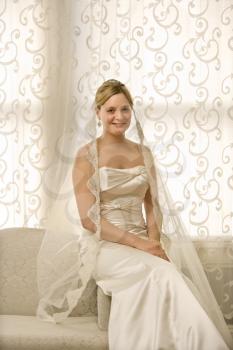 Royalty Free Photo of a Bride Sitting on a Love Seat