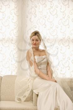 Royalty Free Photo of a Bride Sitting on a Love Seat Making a Funny Expression