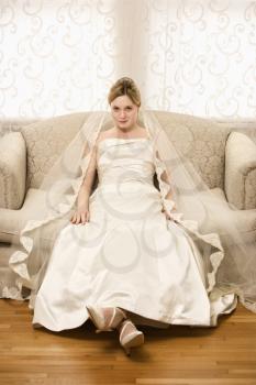 Royalty Free Photo of a Bride Slouching on Love Seat
