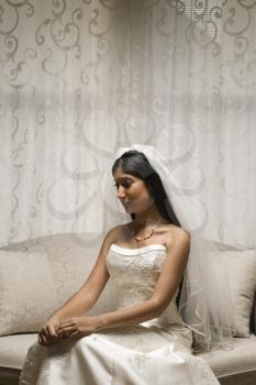 Portrait of an Indian bride sitting on a love seat.