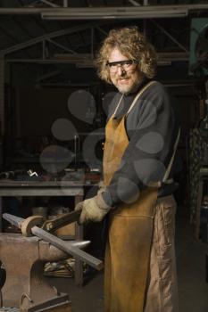 Royalty Free Photo of a Metal Smith Holding an Anvil