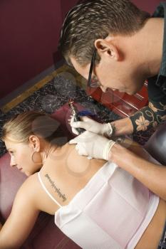 Royalty Free Photo of a Male Tattoo Artist Tattooing a Woman