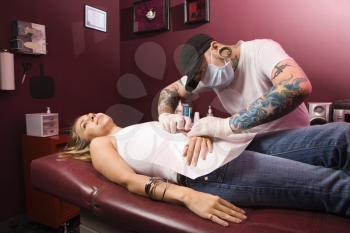 Royalty Free Photo of a Man Giving a Woman a Navel Piercing