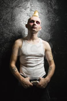 Portrait of mid-adult Caucasian male punk holding belt buckle.