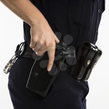Close up side view of mid adult female Caucasian law enforcement officer hand on gun in holster.