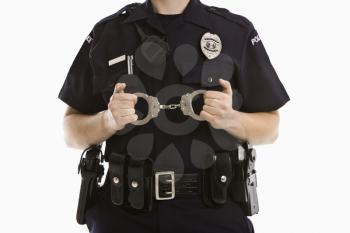 Close up of mid adult Caucasian policewoman holding locked handcuffs.