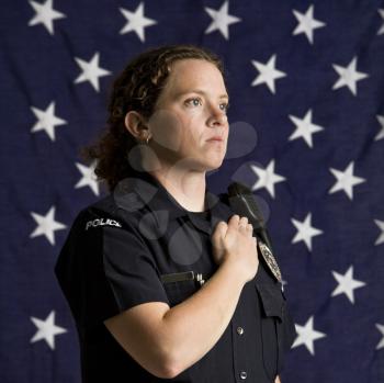 Royalty Free Photo of a Policewoman Pledging Allegiance With an American Flag as a Backdrop
