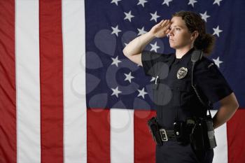 Royalty Free Photo of a Policewoman Saluting With an American Flag as a Backdrop