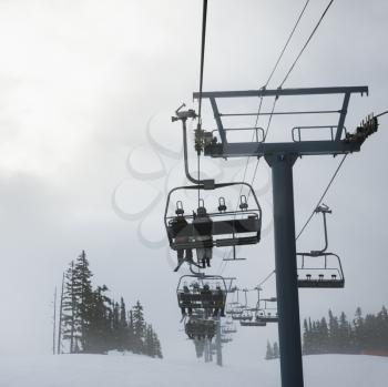 Royalty Free Photo of Skiers Riding the Chairlift in Foggy Winter Weather