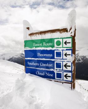 Royalty Free Photo of Snow Covered Sign With Arrows to Slopes