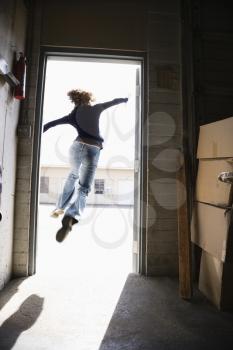 Royalty Free Photo of a Woman Running and Jumping Through an Open Door 