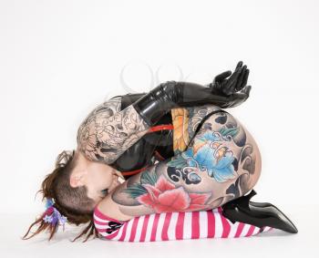 Adult caucasian woman with tattoos sitting on floor.
