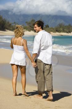 Royalty Free Photo of a Couple Holding Hands Walking on a Beach Smiling in Maui, Hawaii