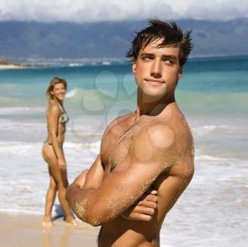 Royalty Free Photo of a Handsome Man Standing on Maui, Hawaii Beach With a Woman in the Background