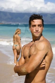 Royalty Free Photo of a Handsome Man Standing on Maui, Hawaii Beach With a Woman in the Background