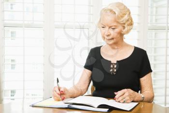 Royalty Free Photo of an Older Woman Writing in a Calendar