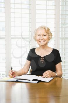 Royalty Free Photo of an Older Woman Writing On a Calendar