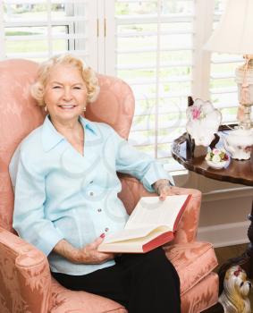 Royalty Free Photo of an Older Woman Sitting in a Chair Reading a Book