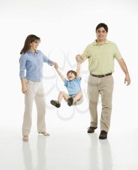 Royalty Free Photo of a Mother and Father Holding Hands With Their Son and Lifting Him Up