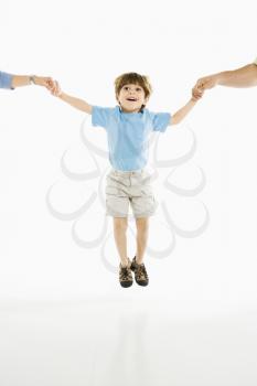Royalty Free Photo of a Boy Jumping Into the Air Holding Hands With His Parents 