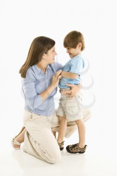 Mother kneeling down with son against white background.